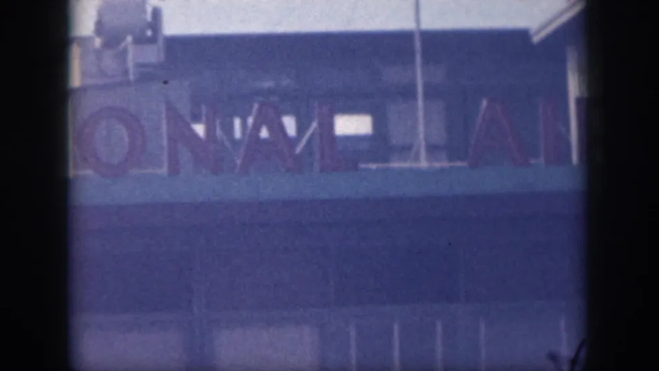 Close 8mm view of airport signage in Oahu, with cropped letters from an international airport sign across a blue facade.