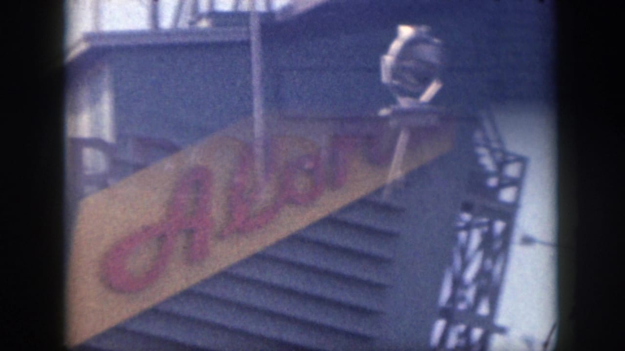 Partial airport sign and diagonal Aloha sign on a blue building facade.