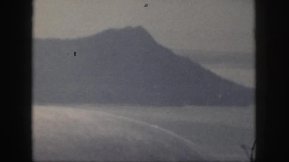 1959 Oahu 8mm view of a blue-gray ridge across water, with a small bird-like speck near the peak.