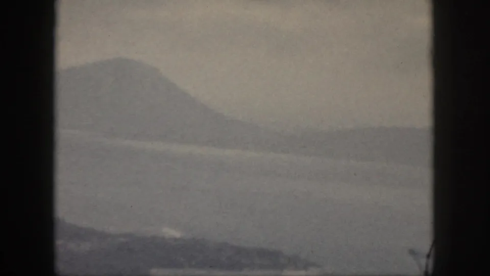 1959 Oahu 8mm frame showing misty water and distant green mountain ridges through a dark window-like border.
