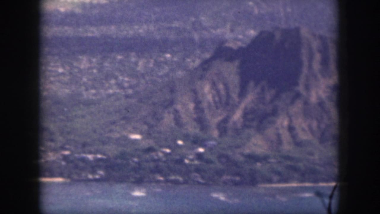 Mountain slope above water and a coastal settlement.