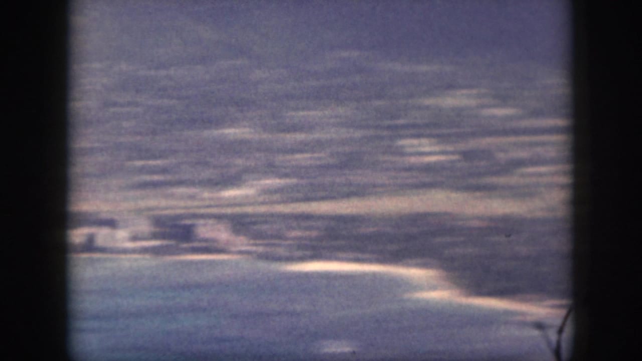 1959 Oahu 8mm view across coastal flats, a curving sandy shoreline, and blue-green water.