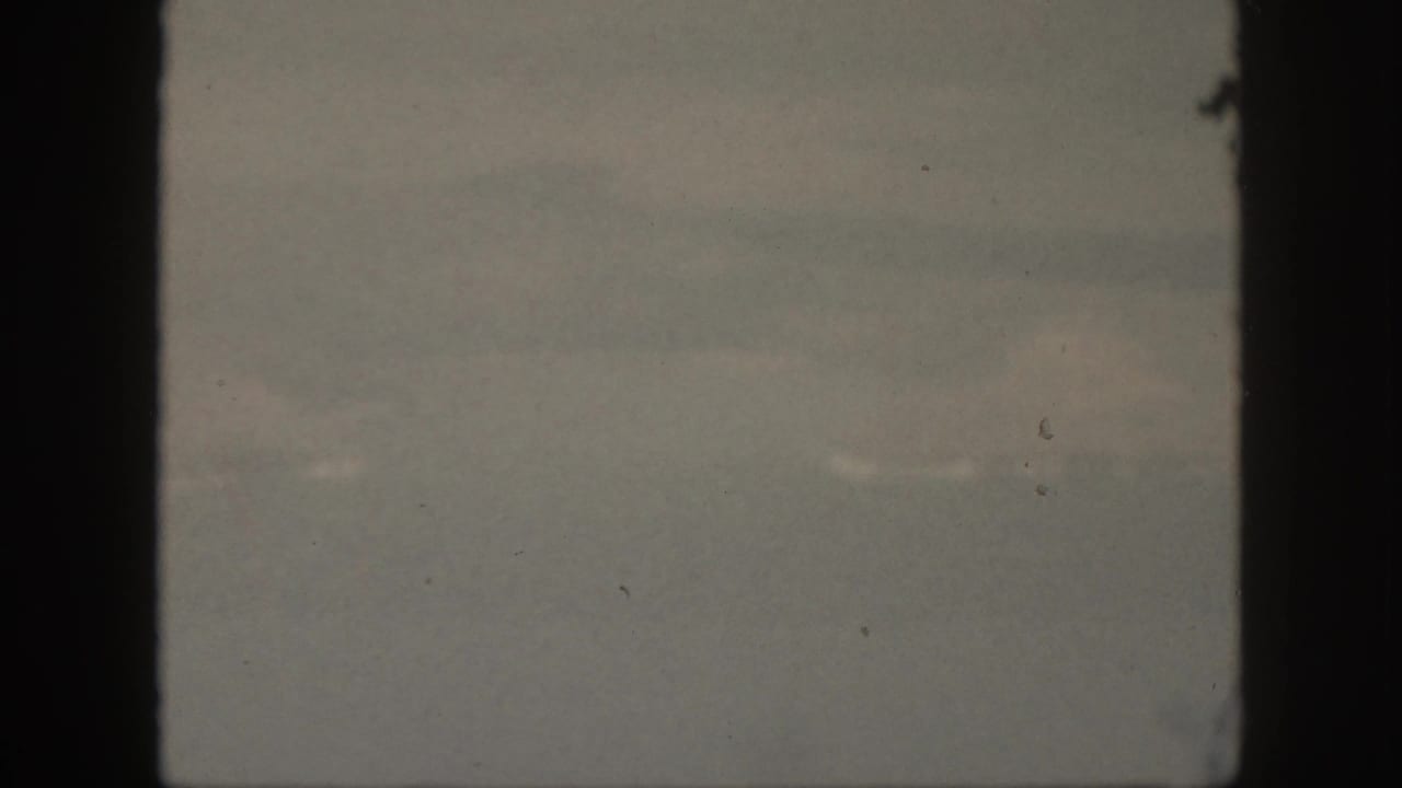 A muted 1959 Oahu ocean view with soft horizon haze, faint water texture, and dark film-gate borders.