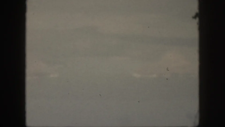 A muted 1959 Oahu ocean view with soft horizon haze, faint water texture, and dark film-gate borders.