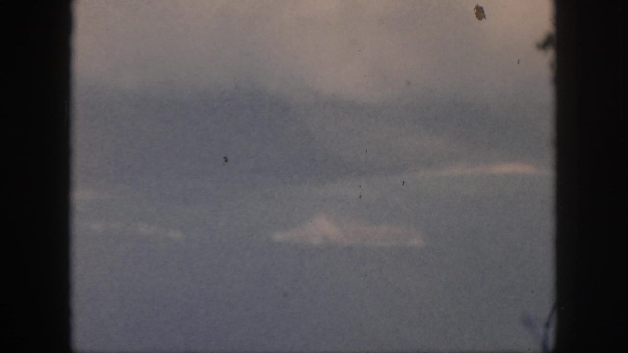 Soft blue-gray horizon and pale cloud shapes framed by dark vertical window edges.