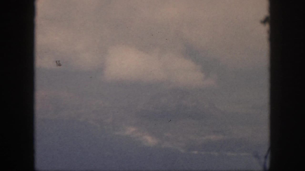 Soft cloud cover seen between dark vertical borders on grainy film.