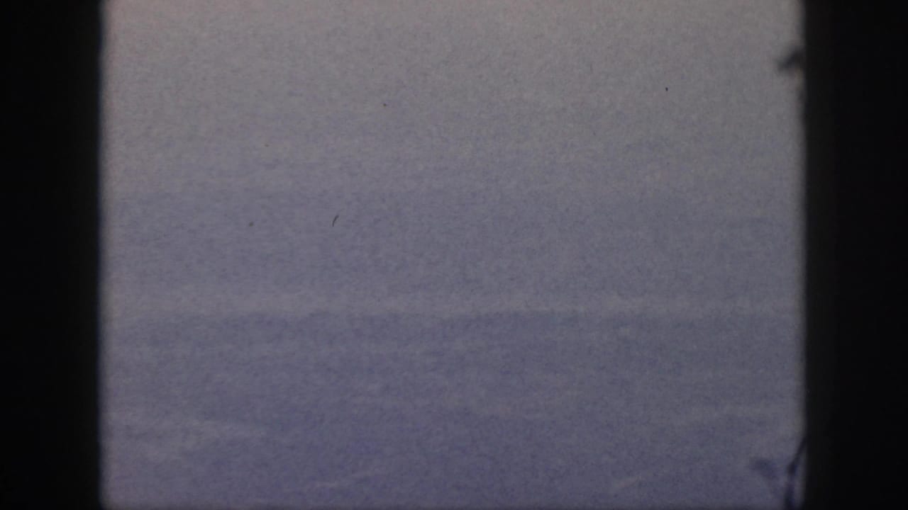 A distant, hazy Oahu aerial view is visible through a passenger window, with aged color and light film specks.
