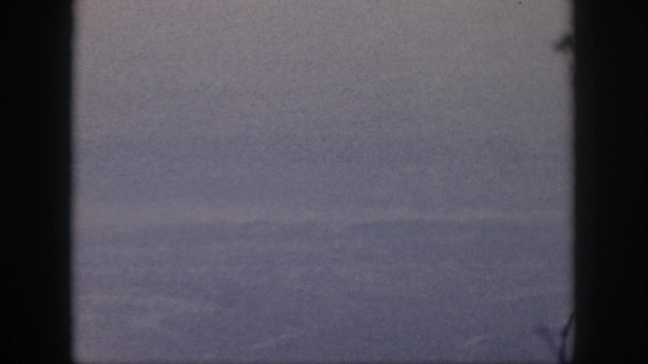 1959 Oahu 8mm frame showing a calm blue ocean and distant horizon through dark window-like edges.