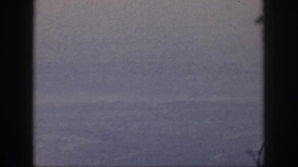 1959 Oahu 8mm frame showing a calm blue ocean and distant horizon through dark window-like edges.