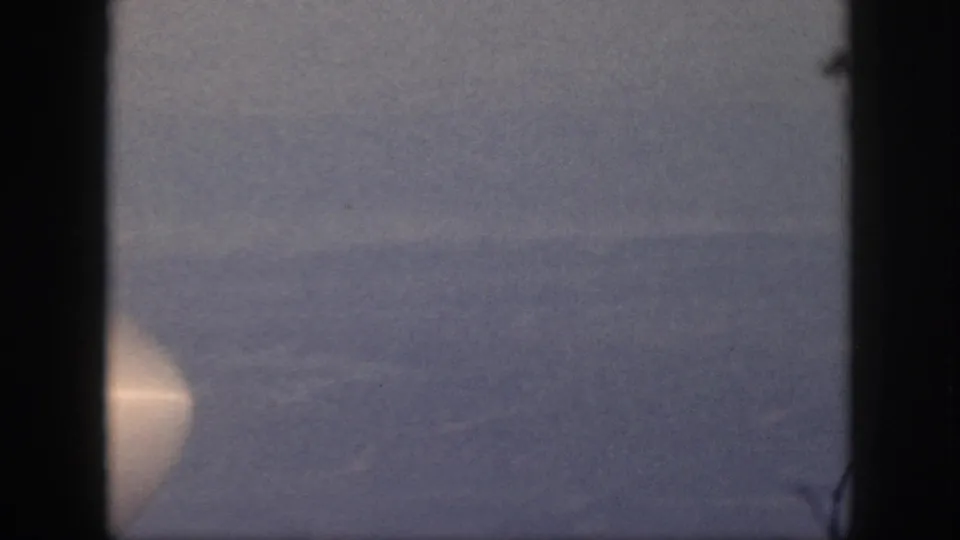 1959 Oahu 8mm still showing calm water, a distant horizon, and a bright circular light at the lower left edge.