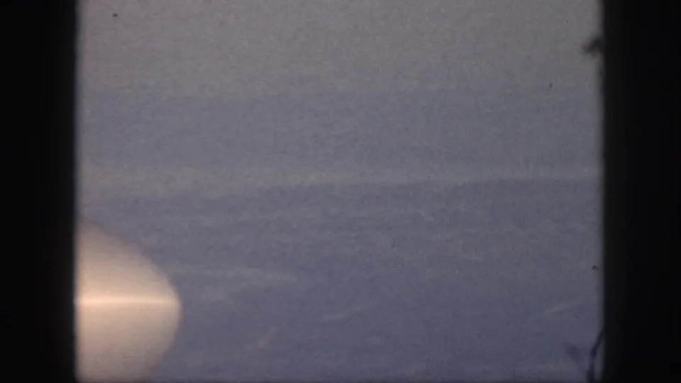 1959 Oahu home-movie frame of a calm ocean horizon with a bright circular light near the lower left edge.