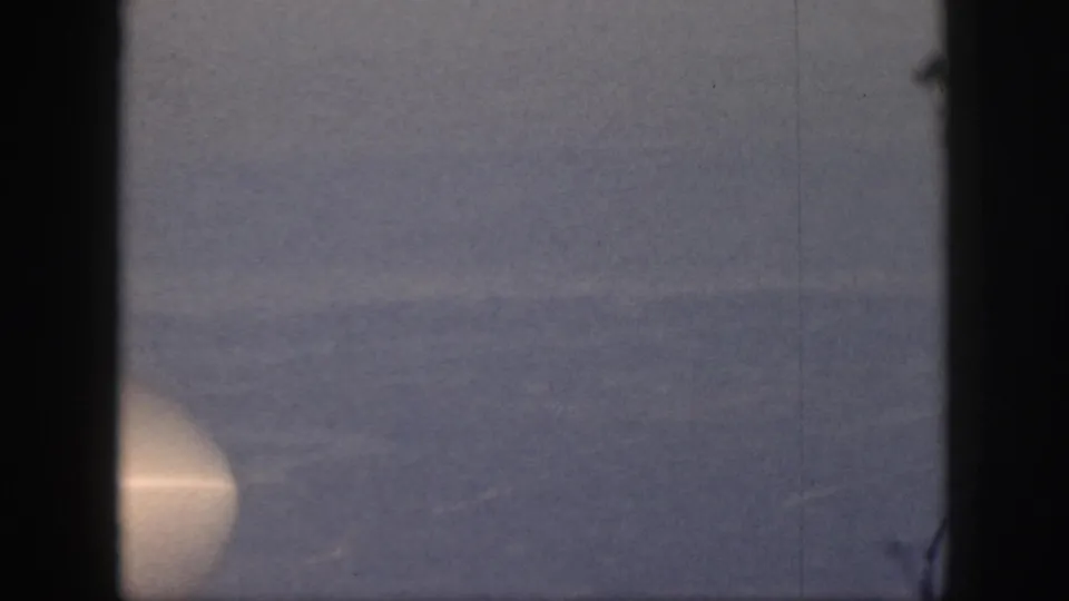 1959 Oahu home-movie frame showing a fog-covered valley with dark window-like borders and a faint bright glow at left.
