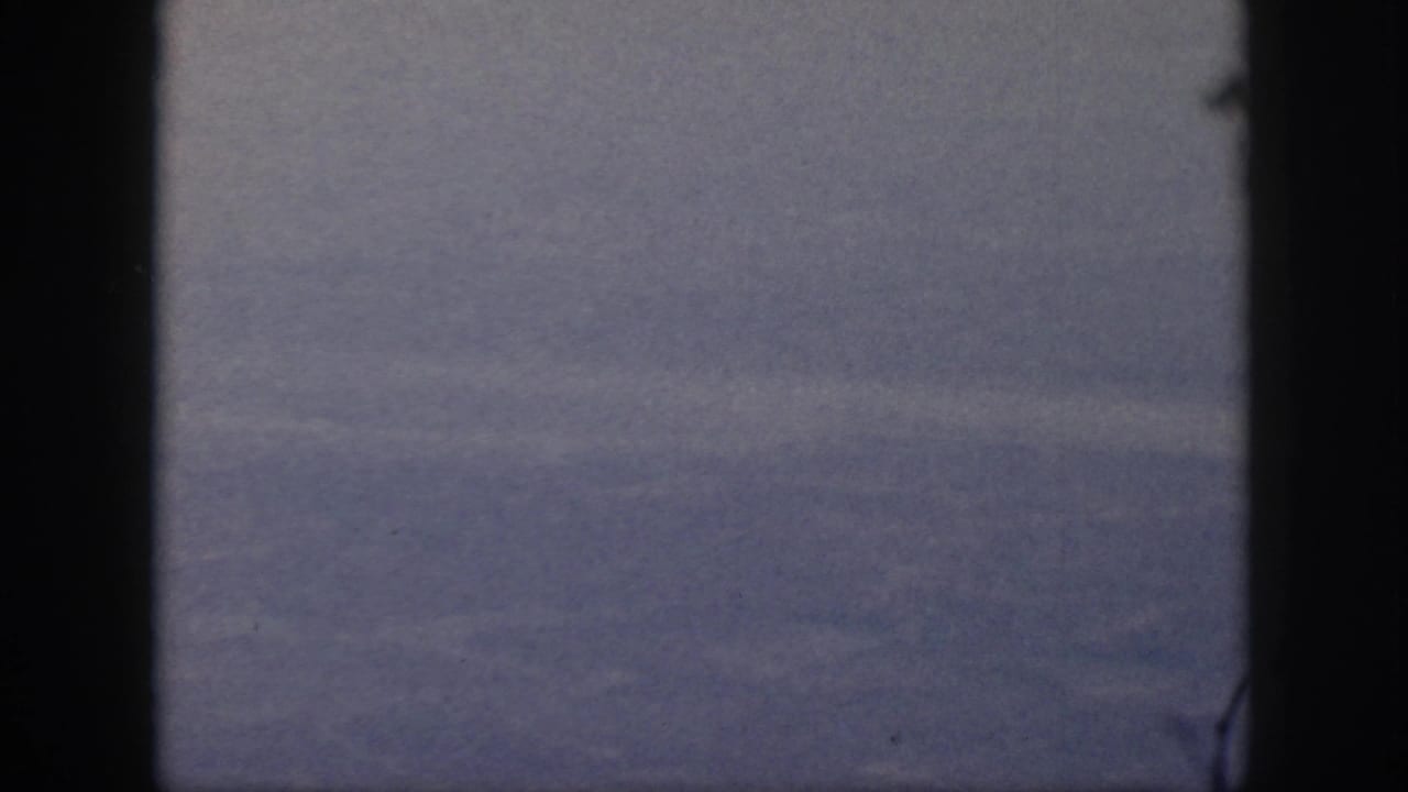 Soft blue-gray fog over a valley framed by dark film borders.
