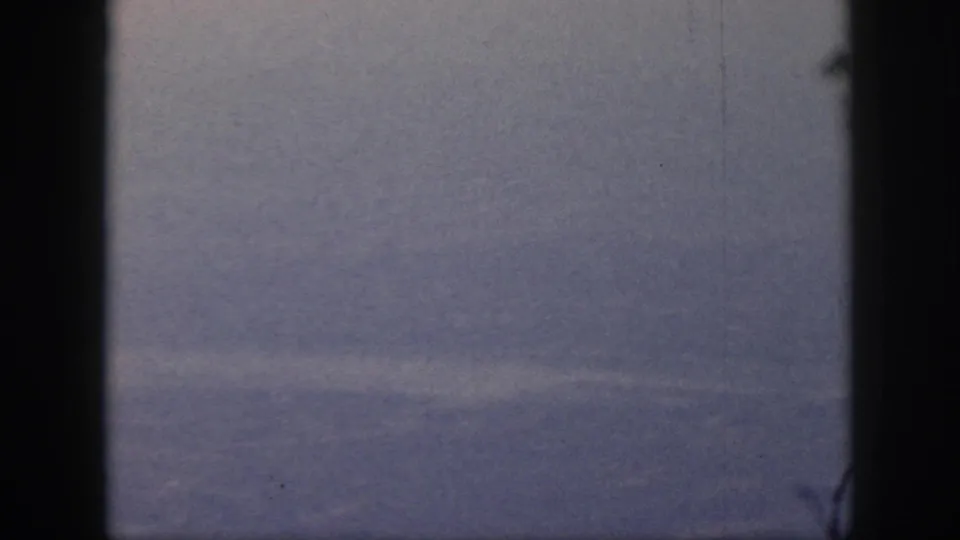 1959 Oahu 8mm frame showing a fog-shrouded valley or forested slope, held in a static composition with dark edge borders.