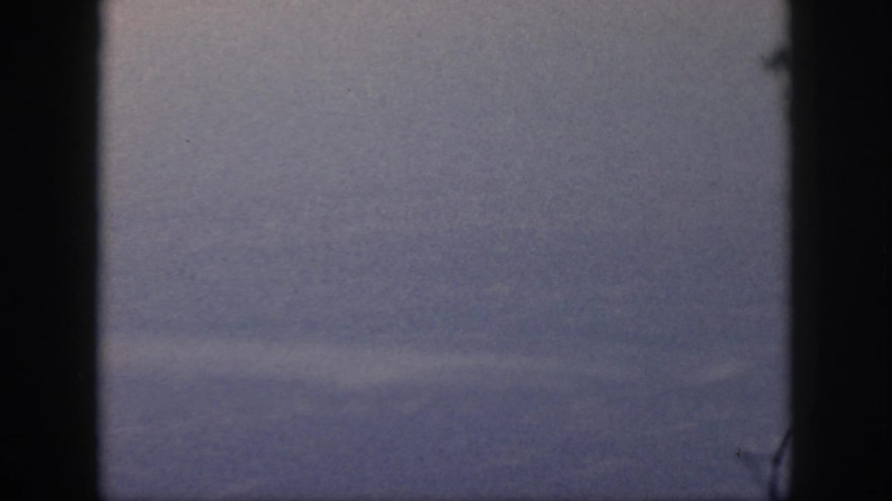 1959 Oahu travel footage showing hazy sky through a dark aircraft-window or film-frame edge, with no people visible.