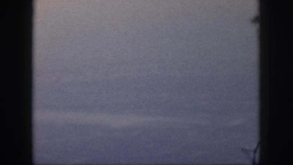 1959 Oahu travel footage showing hazy sky through a dark aircraft-window or film-frame edge, with no people visible.