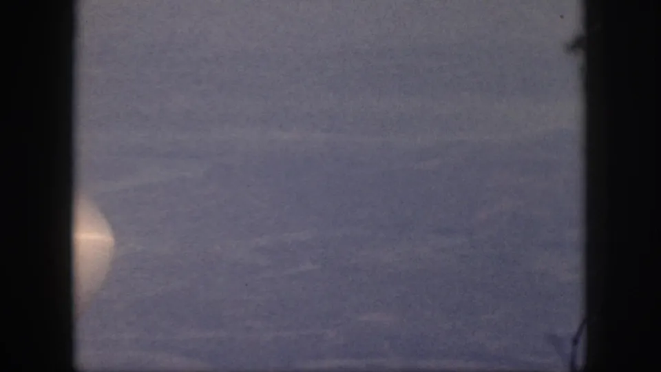 Passenger-window view over Oahu in 1959, with hazy blue sky and part of the aircraft visible at the frame edge.