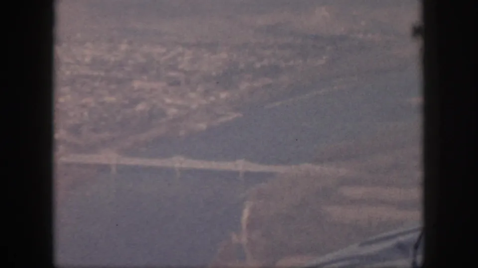Soft 8mm aerial view from Oahu in 1959, with a bridge over water and land forms receding into haze.