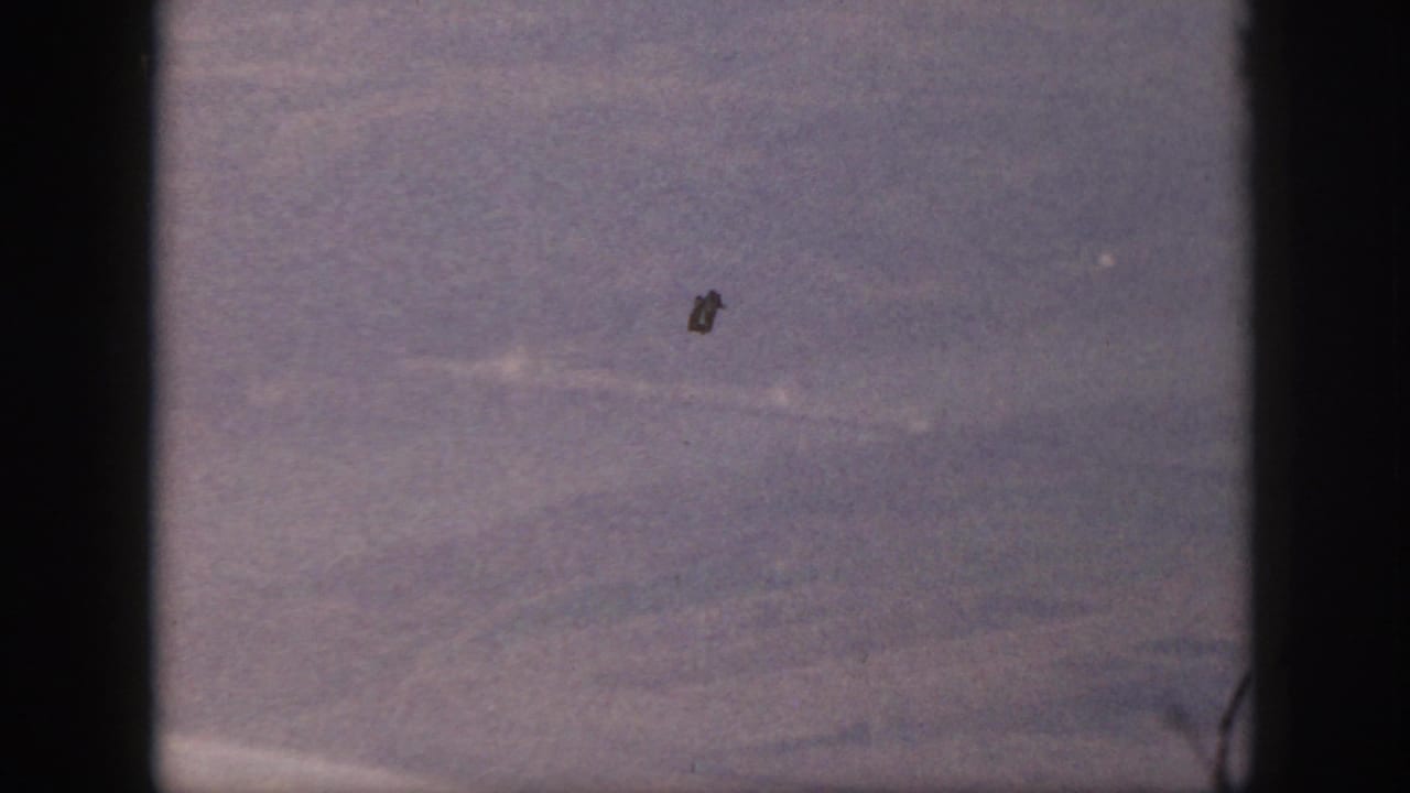 Final 1959 Oahu airplane-window frame with hazy terrain, purple fading, black edge bars, and visible film dust.
