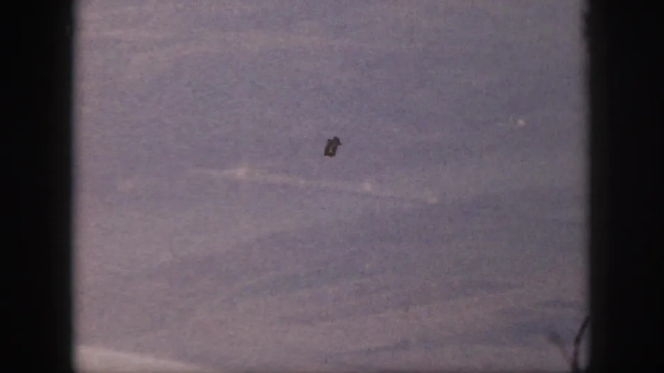 Final 1959 Oahu airplane-window frame with hazy terrain, purple fading, black edge bars, and visible film dust.