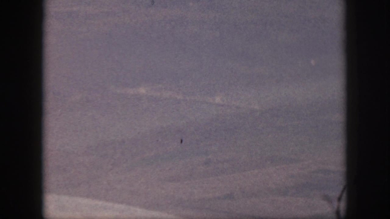 1959 Oahu home-movie frame showing a hazy sky view through dark borders, likely from an airplane window.