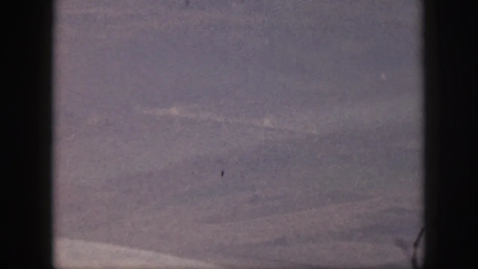 1959 Oahu home-movie frame showing a hazy sky view through dark borders, likely from an airplane window.