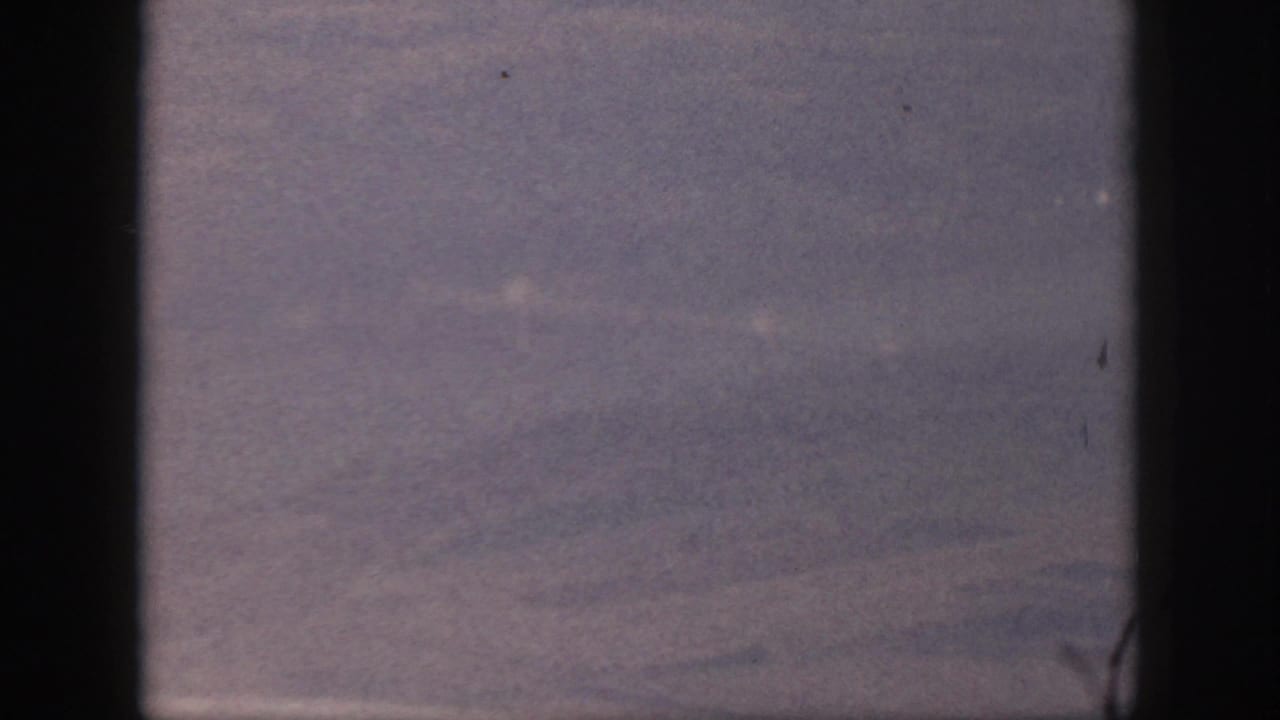 Muted hazy sky with faint horizontal cloud lines and film specks.