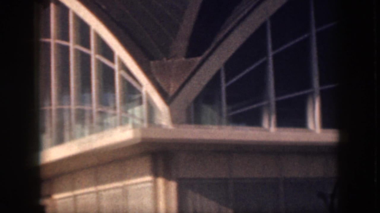 1959 Oahu 8mm frame showing a modern building facade with curved glass, white mullions, and arched roof structure.