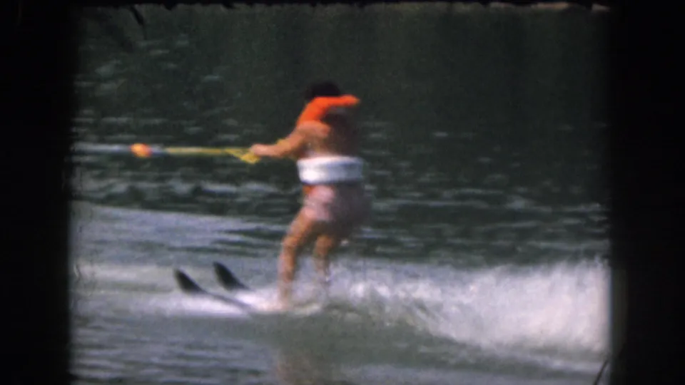 1961 Grand Rapids home-movie frame showing the skier upright and moving across the lake after rising from the water.