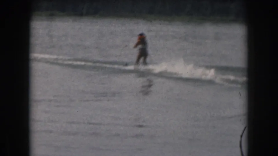 Final 1961 8mm frame of the distant water skier continuing across open lake water near Grand Rapids, Michigan.