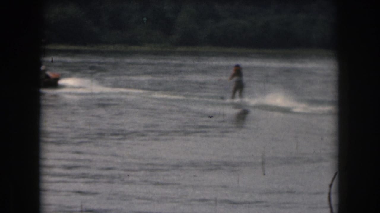 Water skier follows a motorboat across the lake surface.