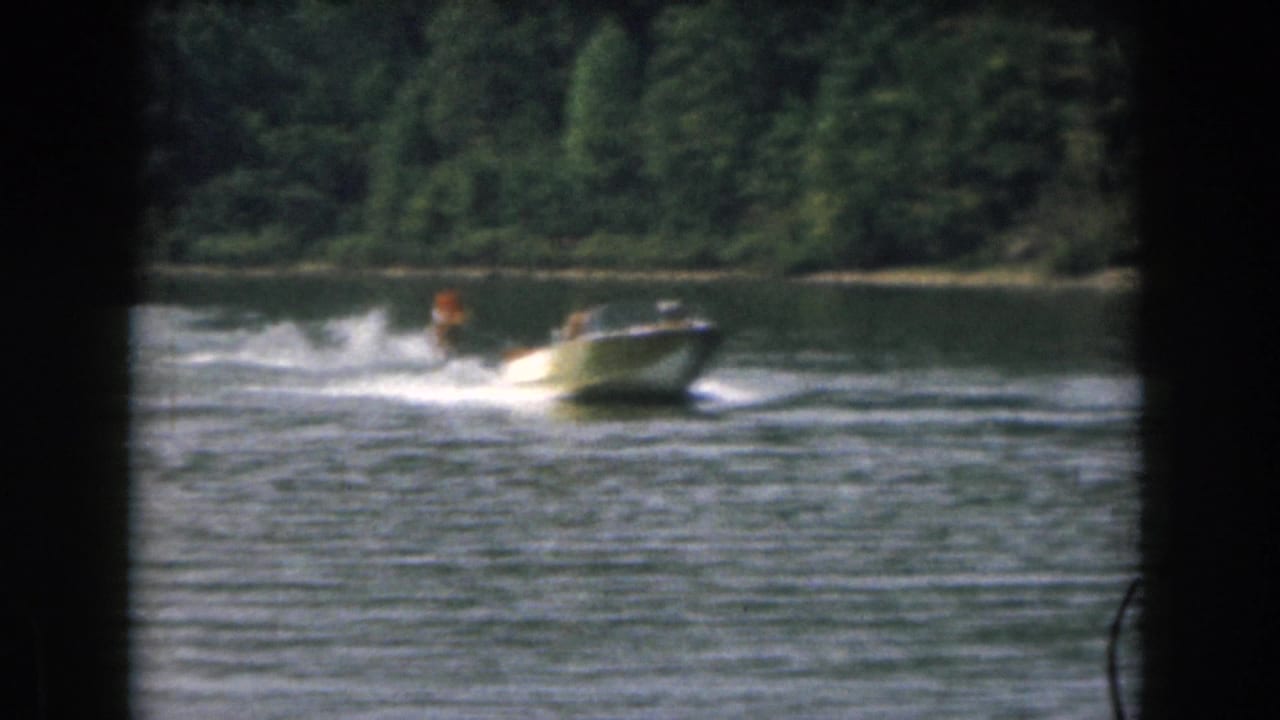 Motorboat and water skier move across the lake, leaving a bright wake behind them.