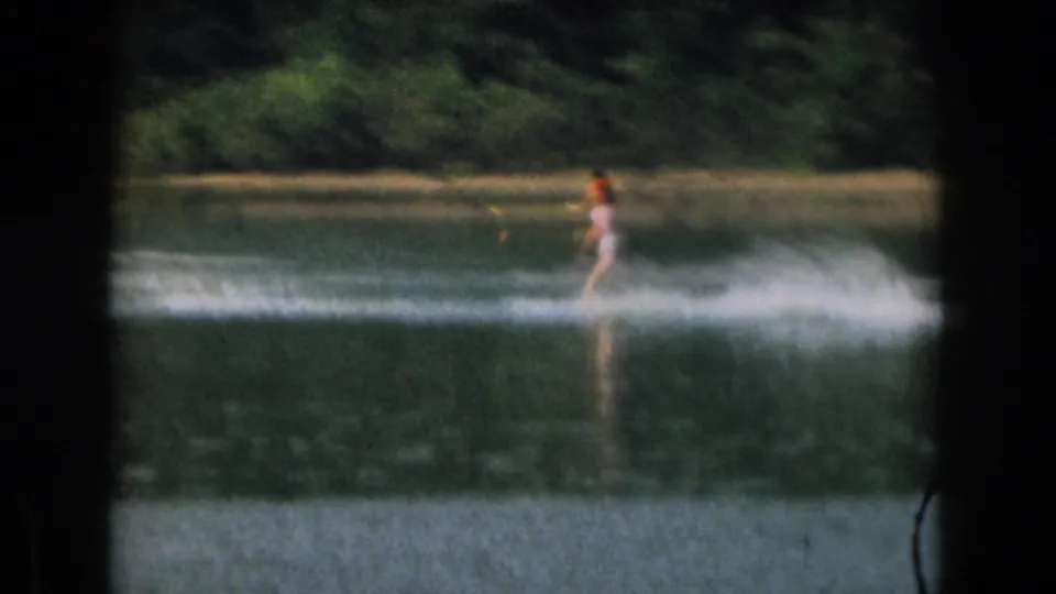 The final frame shows a distant skier continuing across the lake in 1961 Grand Rapids, with heavy spray and a tree-lined shore behind.