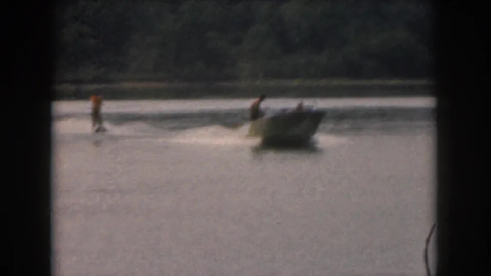 Soft 8mm home-movie view of a motorboat and water skier moving across a lake near Grand Rapids, Michigan.