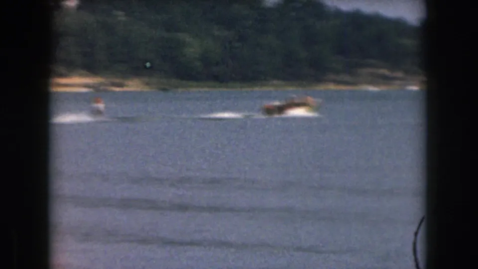1961 Grand Rapids-area lake footage showing a small speedboat pulling a distant water skier across open water.