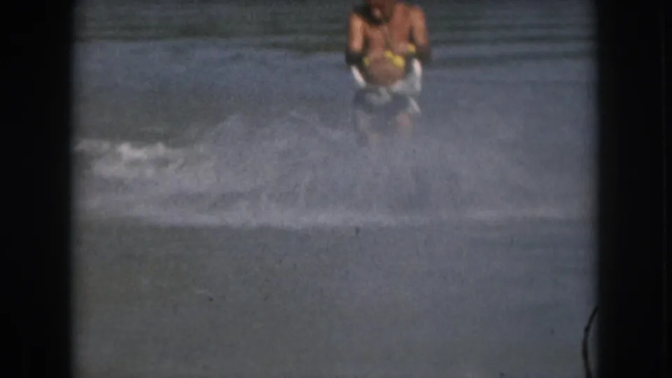 1961 Michigan frame with the skier partly hidden behind spray while holding the tow handle on open water.