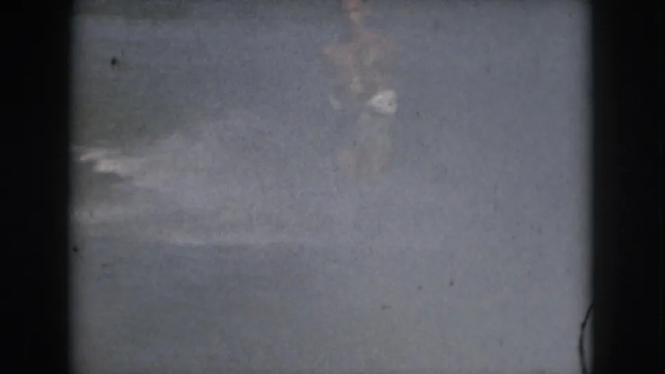 A soft 8mm frame of open water during the water-skiing sequence, with the skier largely out of view and dark gate borders visible.