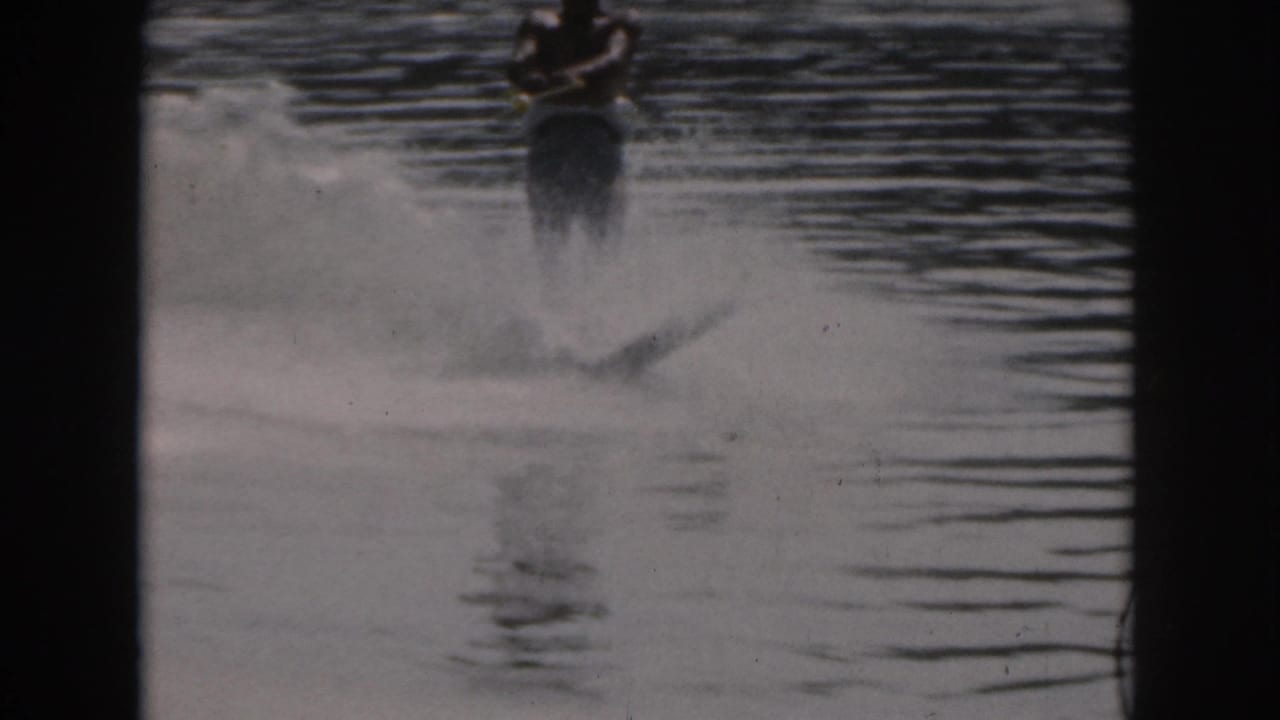 Water skier continues across rippled water with spray trailing behind.