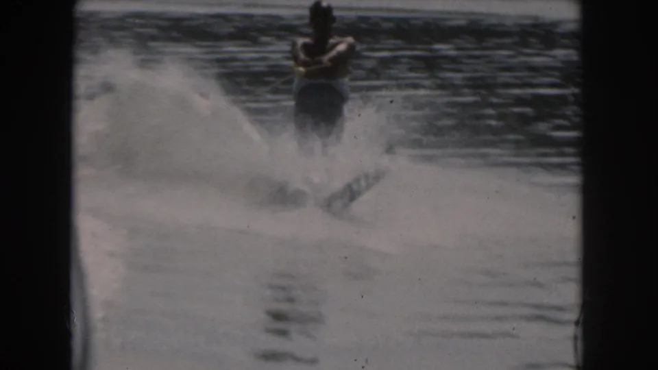 1961 8mm home-movie frame of a water skier cutting through the lake and producing a wide spray.