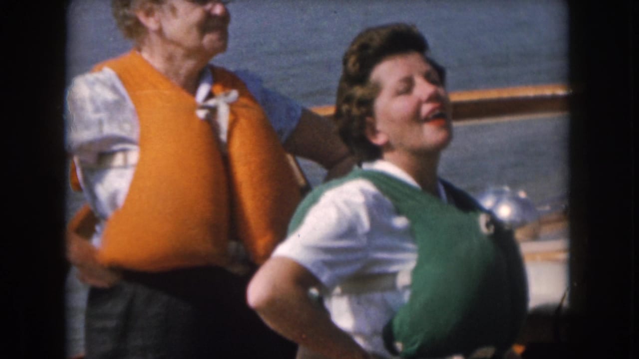 Adults in life vests sit on a boat, with one woman smiling near lake water.