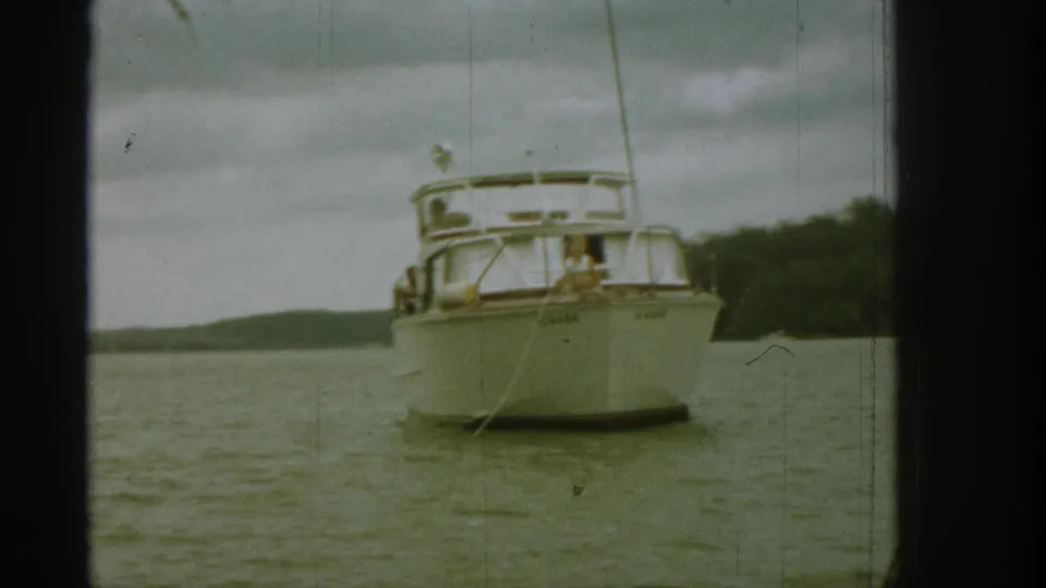 1961 Michigan home-movie frame with the cabin boat approaching front-on and a person near the bow.