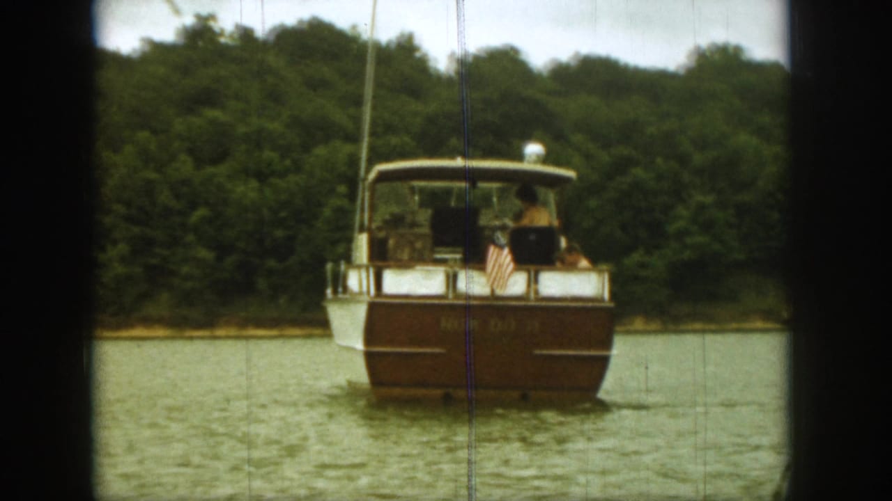 Motorboat centered on the lake with passengers and a small stern flag.