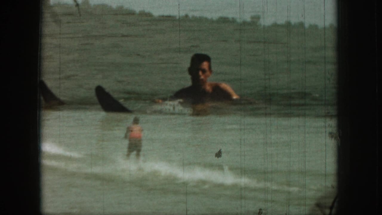 1961 Michigan 8mm frame with a waterskier on a lake and a superimposed floating man visible in the foreground water.