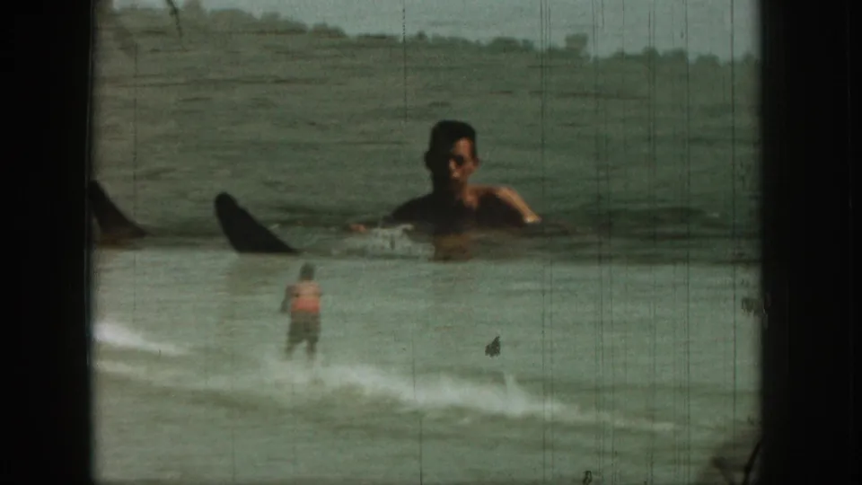 1961 Michigan 8mm frame with a waterskier on a lake and a superimposed floating man visible in the foreground water.