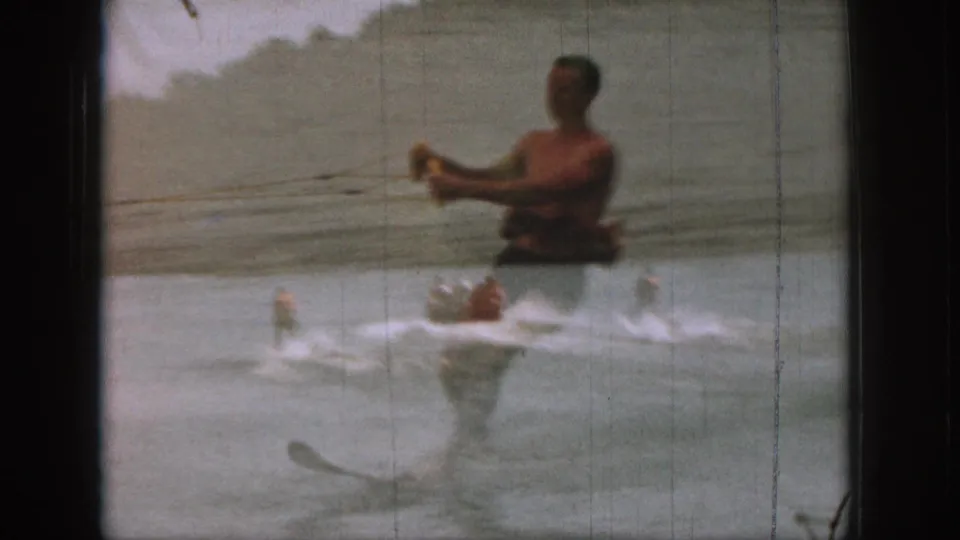 A 1961 Michigan lake scene shows a water skier pulled by boat, with soft exposure and visible film scratches.