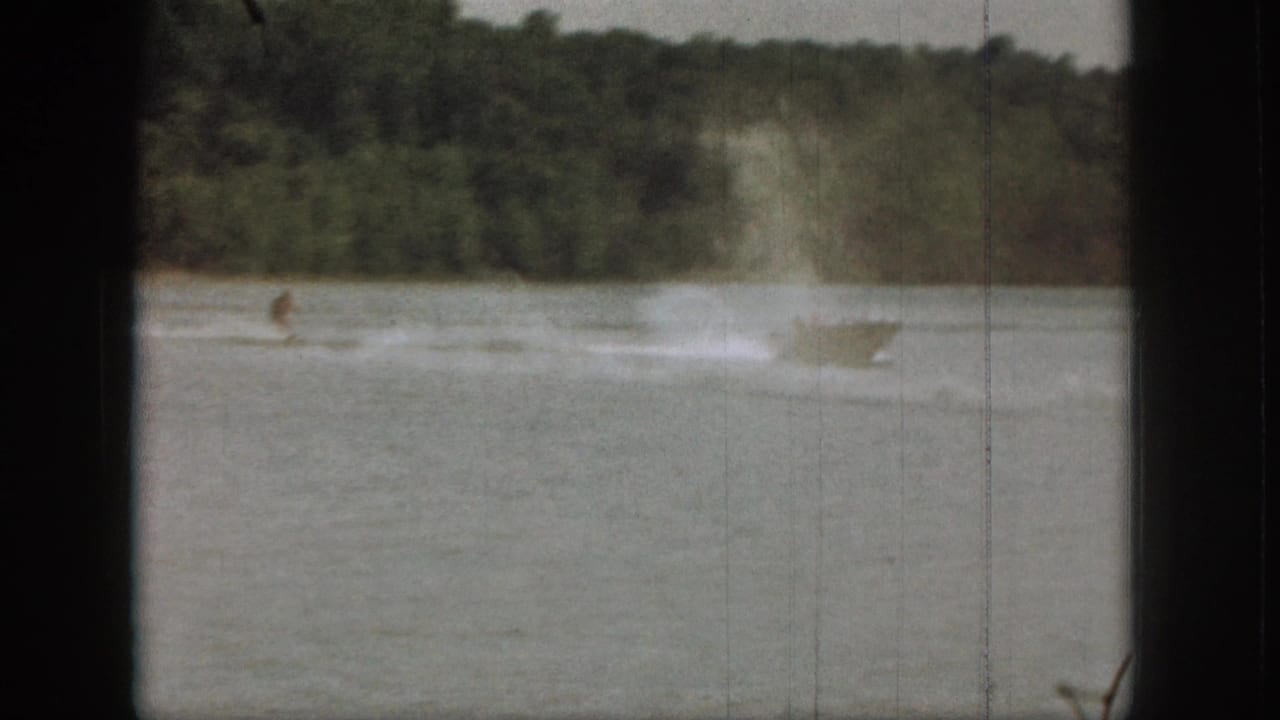 Waterskier on a lake behind a motorboat with trees along the far shore.