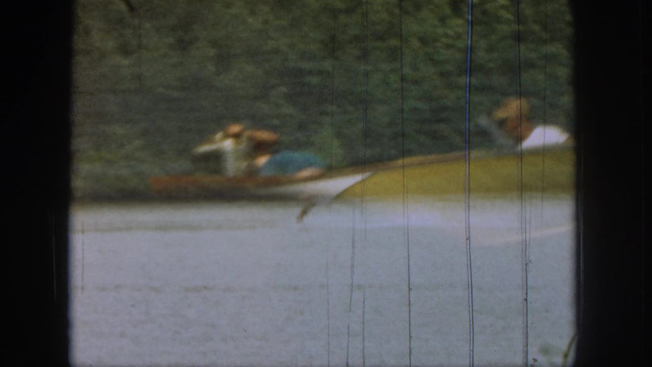 Water skier near a boat window frame on a tree-lined lake.