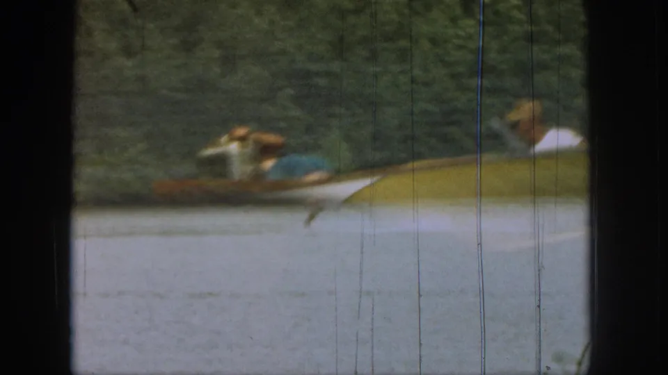 1961 Michigan 8mm frame showing a distant water skier crossing a lake, seen through a dark boat-window frame.