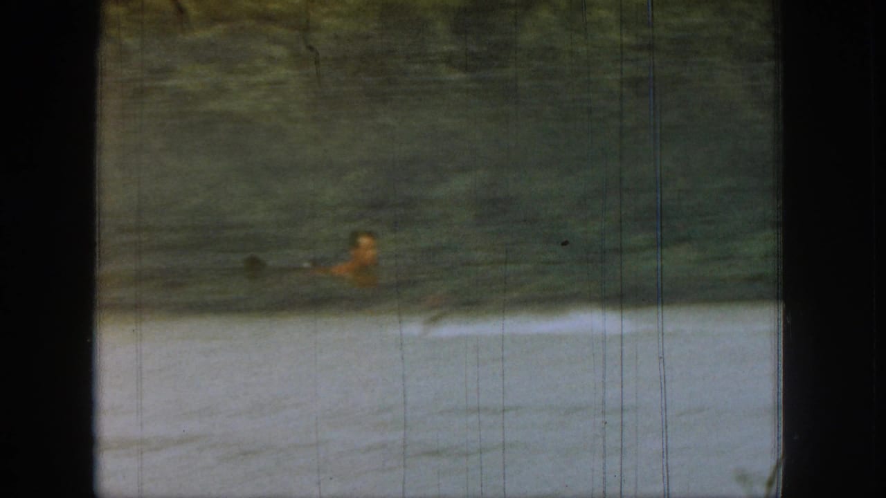 Distant water skier gliding across a lake beside a dark window frame.