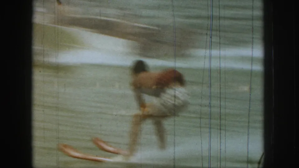1961 Michigan home-movie frame showing the skier losing balance as the skis angle across the wake.